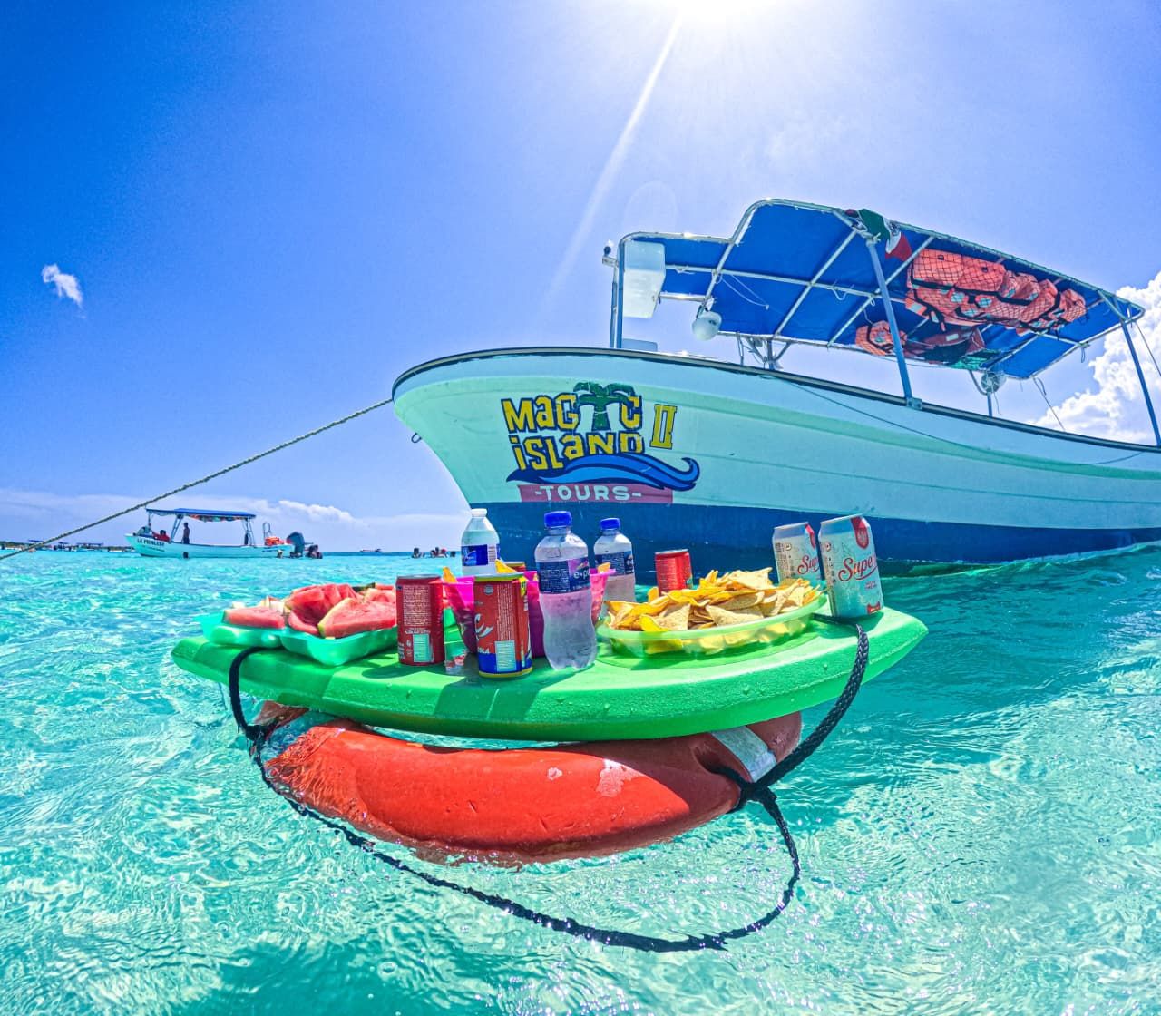 Lancha de Magic Island Tours con una mesa flotante sobre el agua turquesa de Cozumel