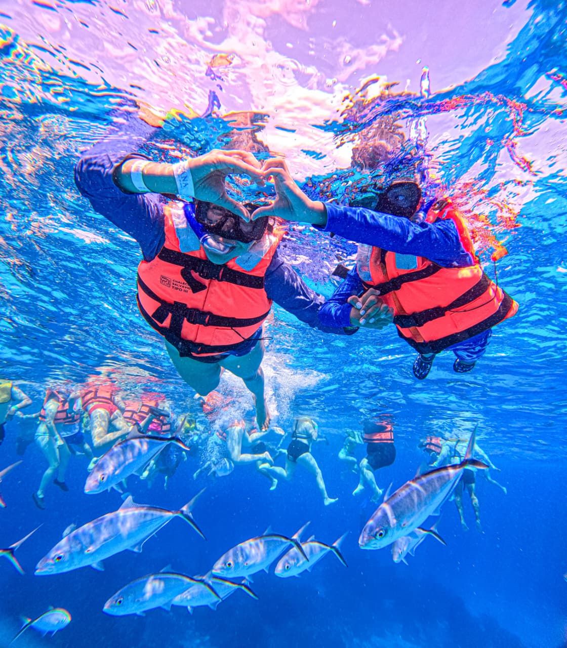 Dos snorkelistas formando un corazón con las manos bajo el agua