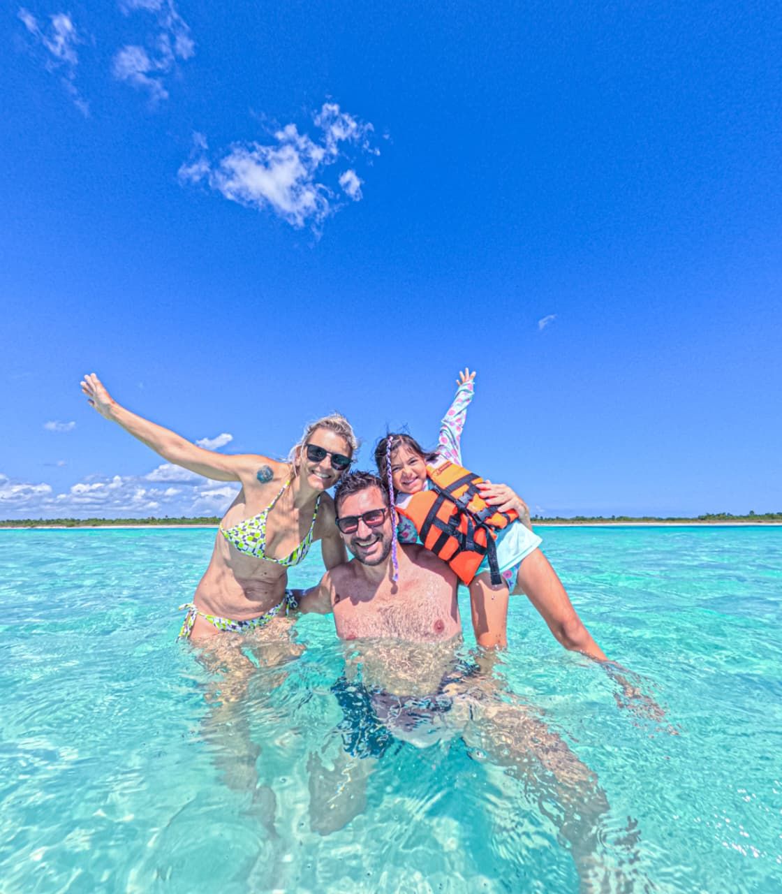 Familia sonriendo en el agua transparente de Cozumel