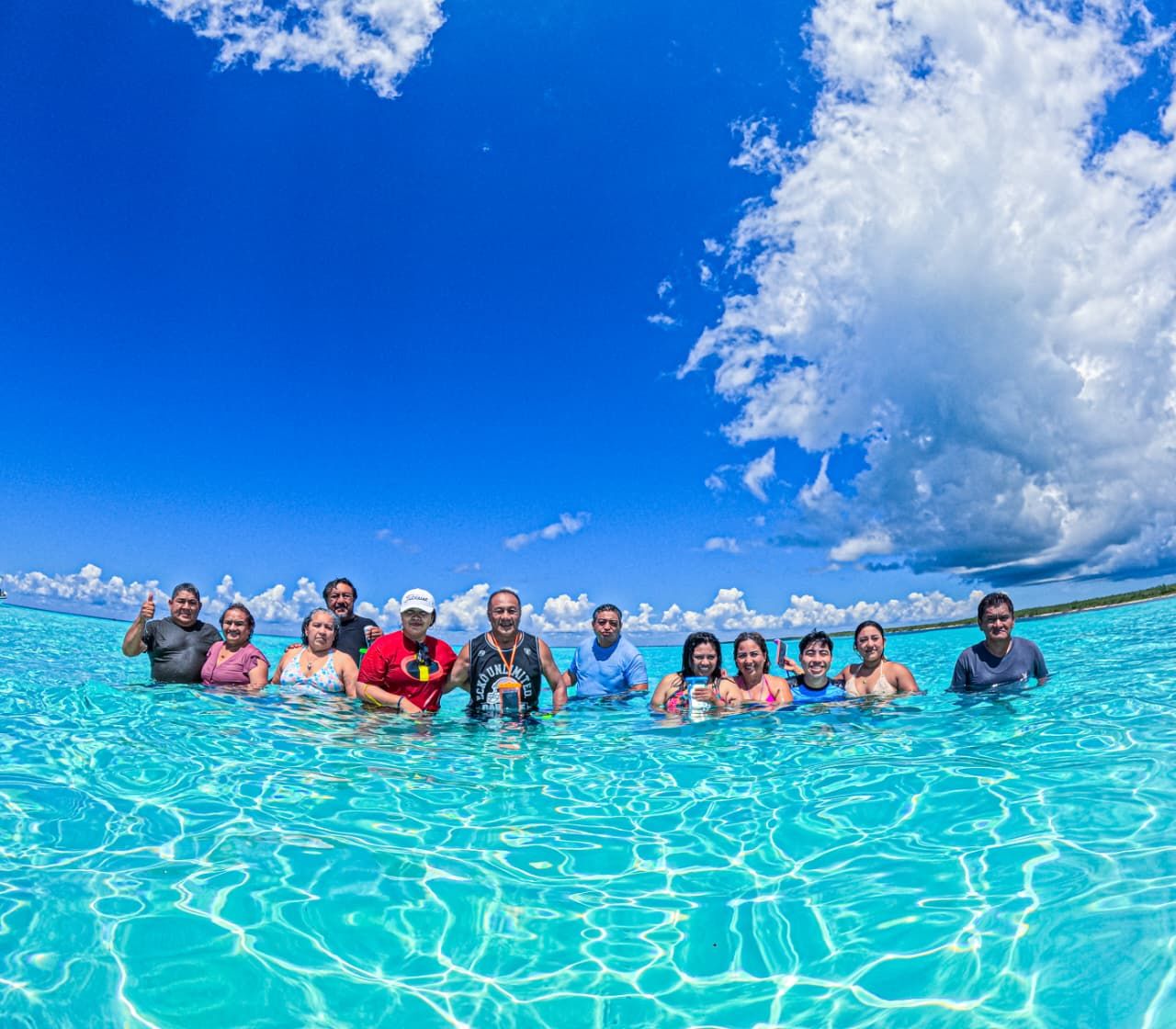 Grupo de viajeros sonriendo en el agua turquesa de Cozumel