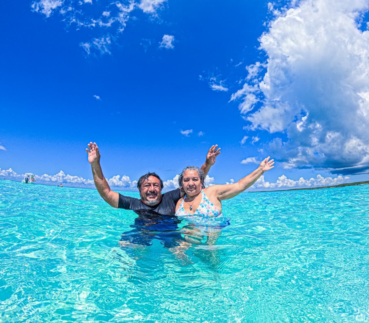 Pareja con los brazos en alto disfrutando del agua turquesa